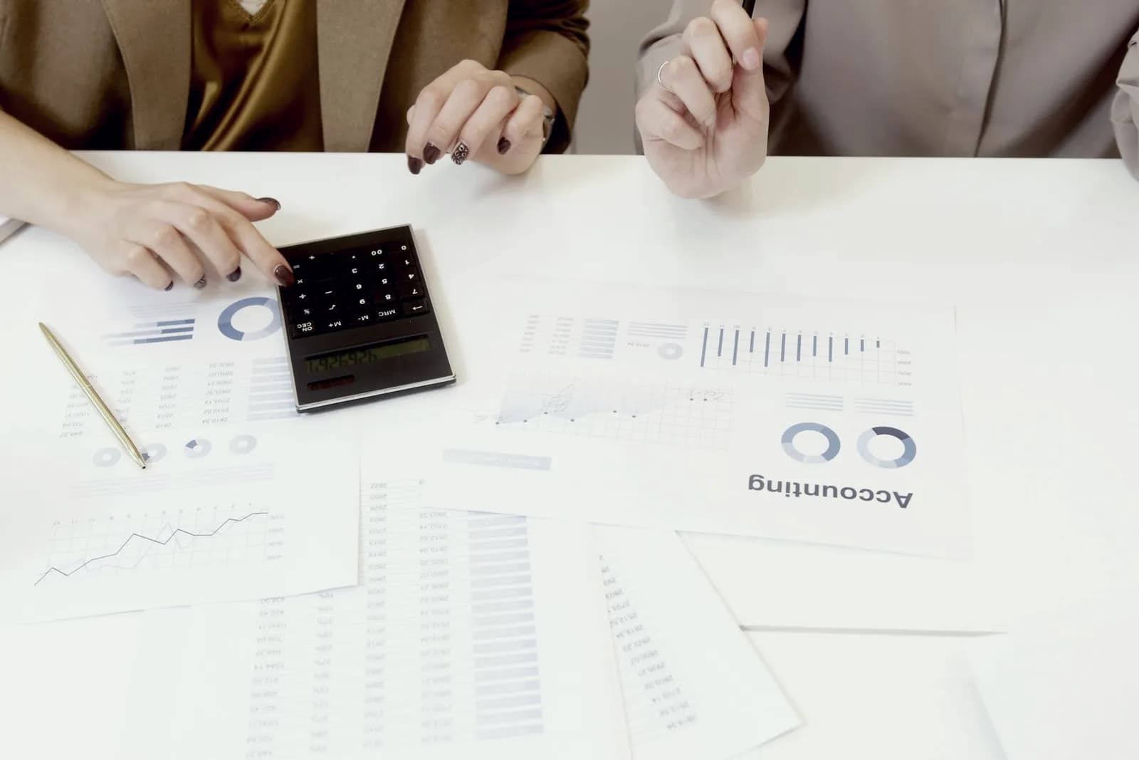 Два специалиста изучают финансовые документы и работают с калькулятором, оценивая показатели активов